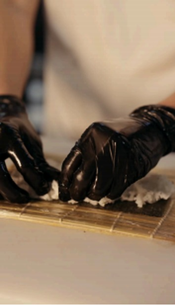 Transition video frame: gloved hands plating on a woven mat